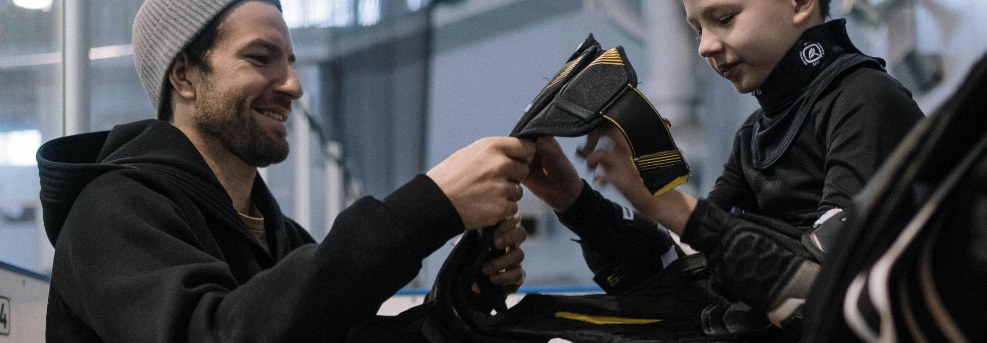 A Man Helping a Boy Wear Ice Hockey Sports Gear